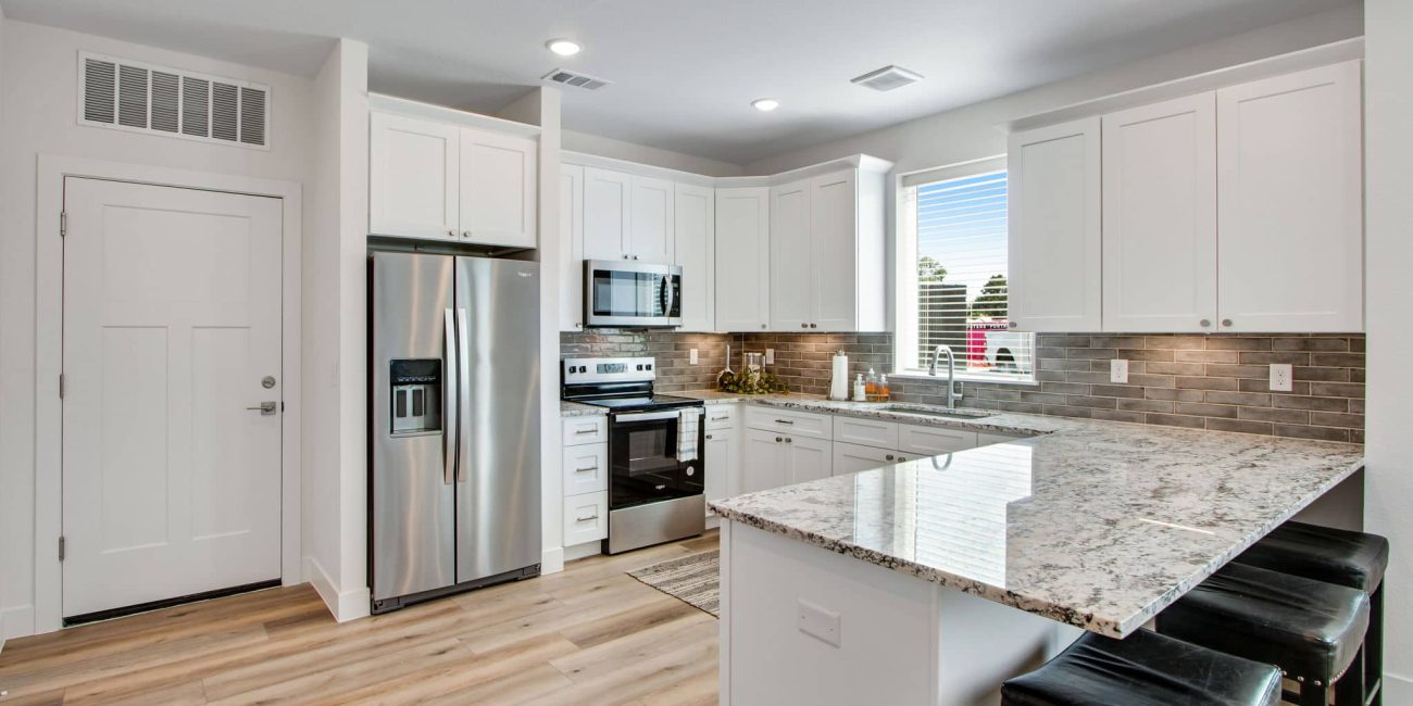 Bright kitchen interior at Westlake Commons featuring white cabinetry, stainless steel appliances, granite countertops, and a large window allowing for natural light.